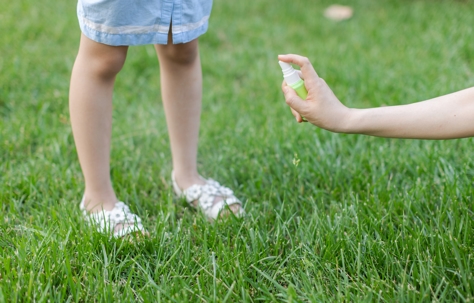 Mother sprays mosquito repellent for daughter.