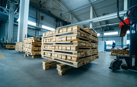 warehouse interior with two pallet jacks and several pallets stacked on each jack